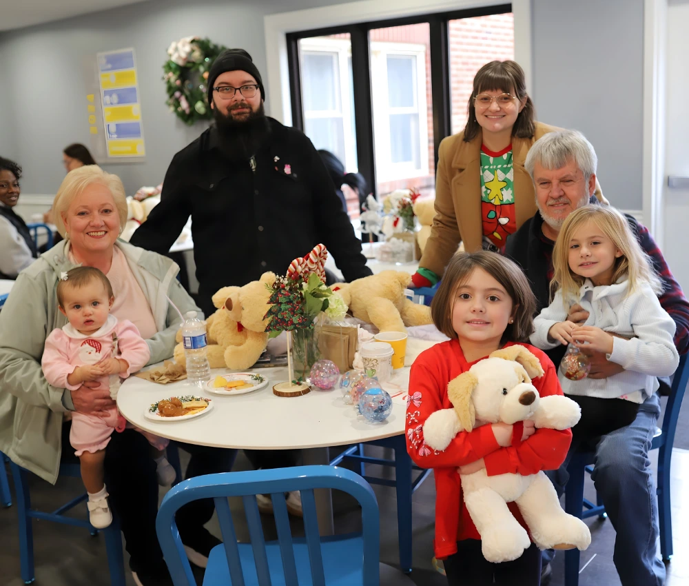 family gathered around table with teddy bears and other gifts