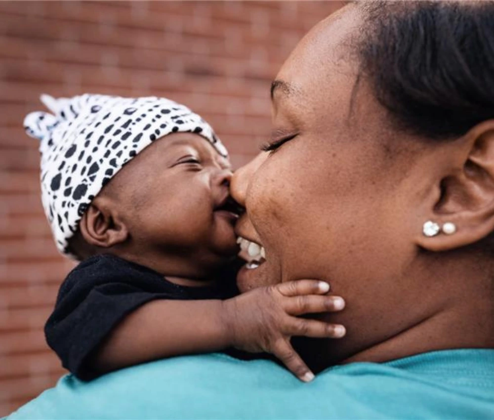 mother holding newborn baby closely face to face with noses touching