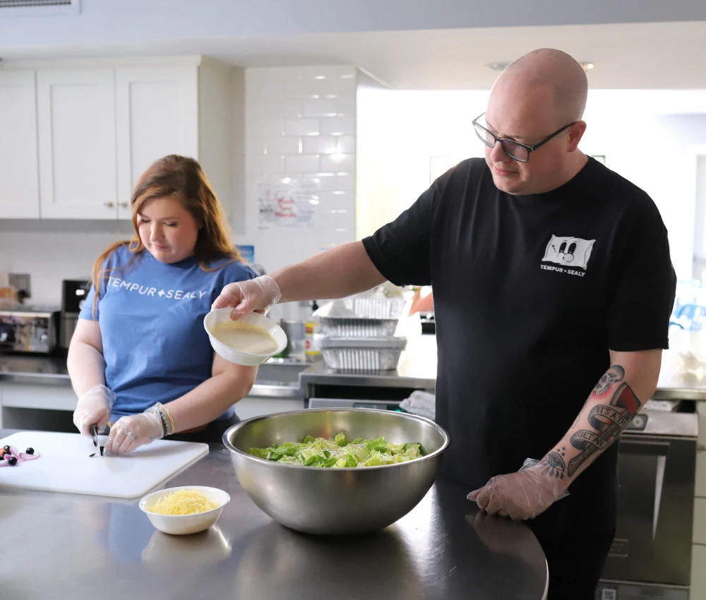 two volunteers working to prepare a meal for our families