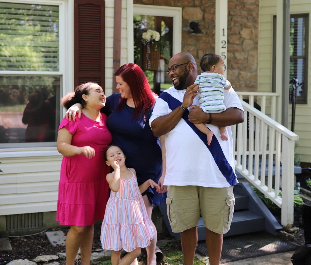 mother and father with their three children gathered outside for a family photo